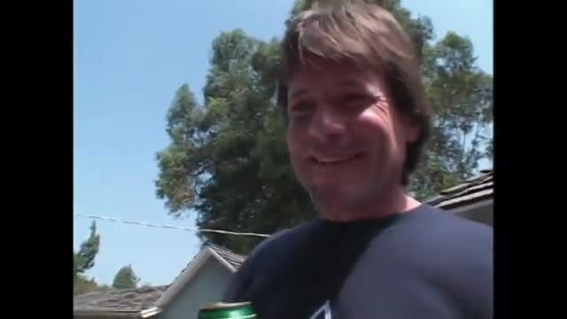 Smiling older man holding beer in bright sunlight