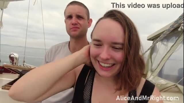 Smiling woman on boat with man behind her, casual outdoor scene