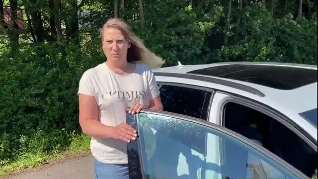 Julia Winter standing by car in industrial park wearing white t-shirt and short skirt