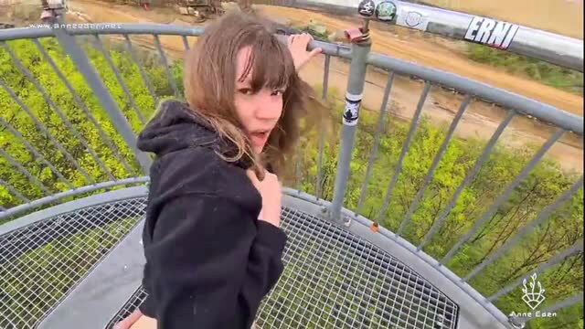Brunette in black hoodie flashing on windy outdoor viewing platform
