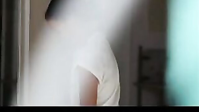 Blurry voyeur view of seductive Asian woman in white top by window