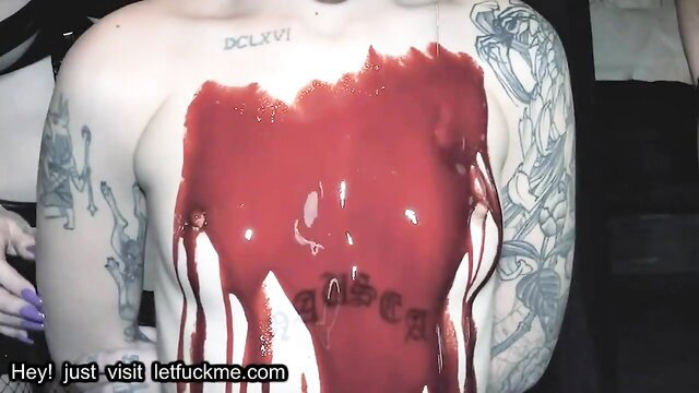 Tattooed guy covered in fake blood with 'letfuckme.com' on chest in Halloween orgy