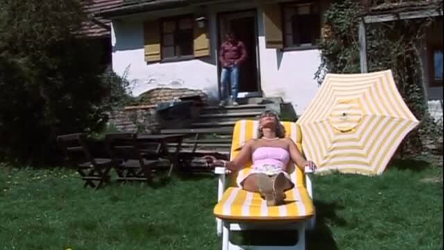 Mature woman in pink top sunbathing on striped lounge chair