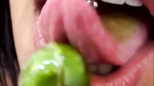 Havana Ginger licks green candy seductively on tongue closeup