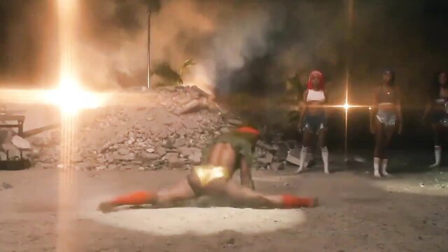 Black women in gold thongs doing sexy splits in fiery night scene