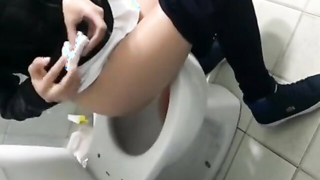 Asian girl in skirt and stockings cleans toilet seat then pees