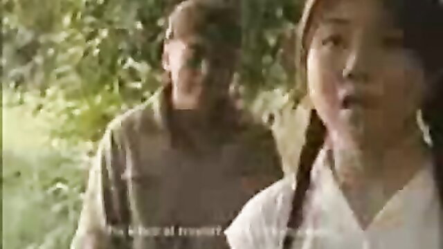 Young Japanese girl with braids walks with older soldier in jungle