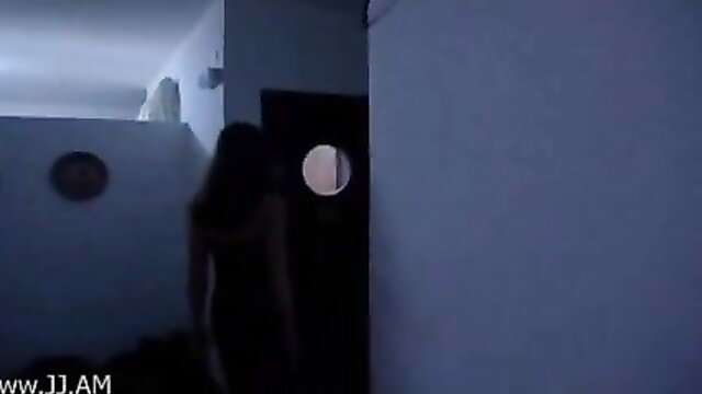 Silhouette of slim Asian woman with long hair at door with peephole in dim light