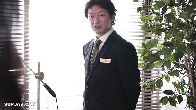 Handsome Japanese salaryman in suit smiles confidently at camera