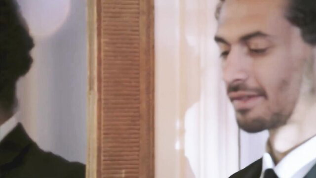 Sophie Dee gazing seductively in mirror, elegant suit, big booty star