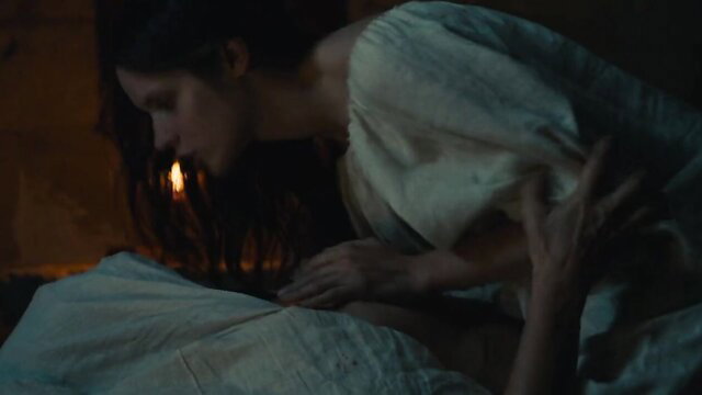 Benedetta lesbian nude scene, woman leaning over bed in dim light