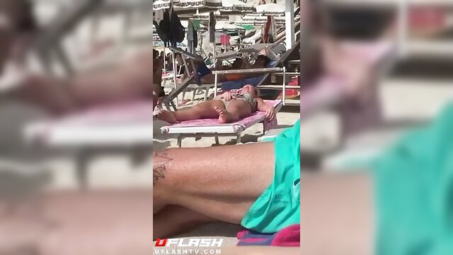 Tattooed MILF rubs pussy on pink beach lounger in public