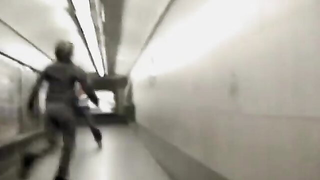 Blurry woman in tight pants running down lit tunnel corridor