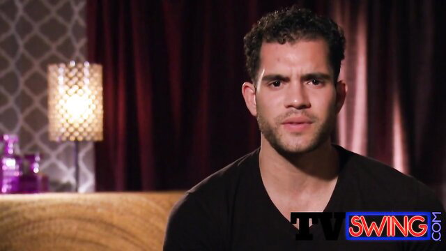 Handsome curly-haired Latino man in black V-neck shirt interview style