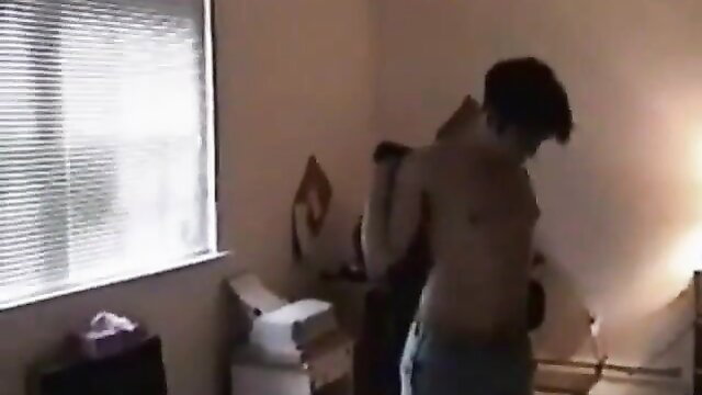 Shirtless young Asian guy hugging from behind in dimly lit bedroom