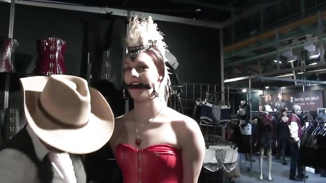 Amateur ponygirl in red corset gagged, pulled by cowboy at fetish fair