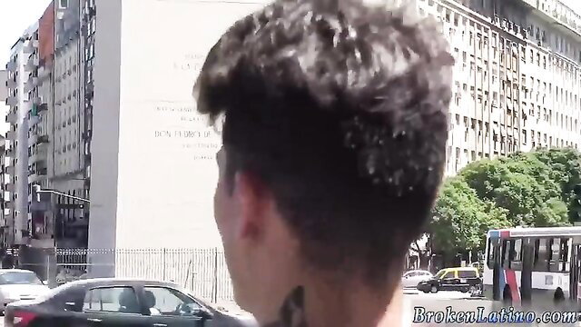 Latino gang member with curly hair and neck tattoo in urban street scene