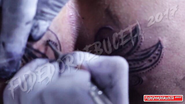 Mar cio Baiano getting tribal tattoo on chest by gloved artist