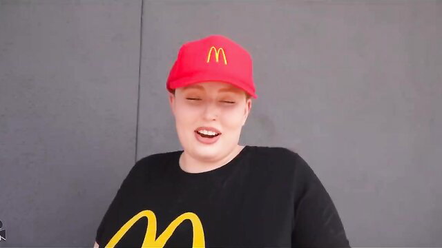 Chubby pale girl in McDonald's hat and shirt smirks playfully