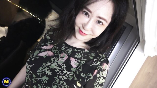 Asian mature woman smiling in floral butterfly dress, sexy cleavage tease