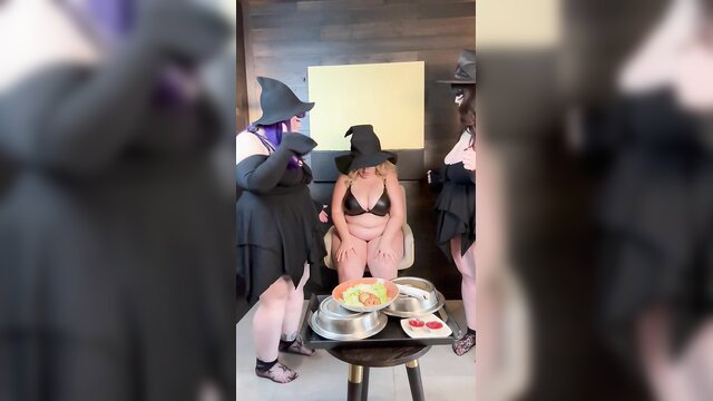 Fat witches in costumes feed busty blonde friend from bowls