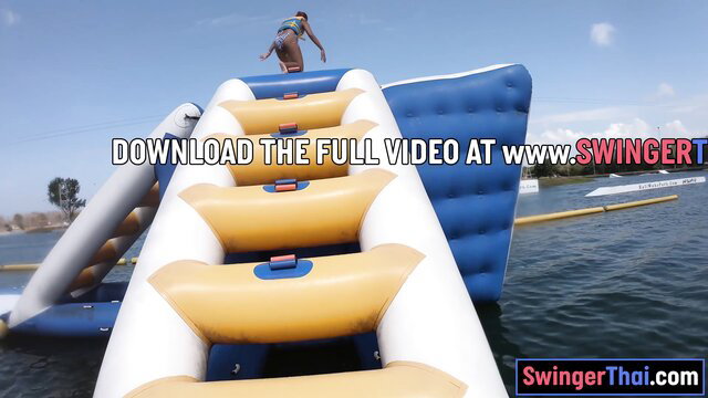 Thai guy jumping on inflatable water slide at park, perfect ass GF video