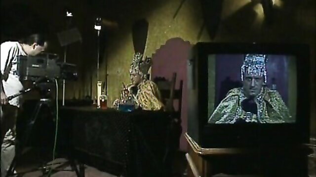 Pharaoh queen in gold headdress on TV, film crew shoots adult scene