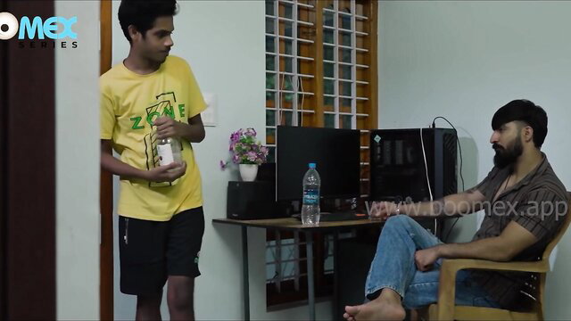 Two young Indian men in casual clothes chatting in room, Boomex watermark