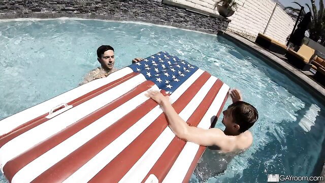 Two hot guys floating massive US flag raft in pool on 4th of July POV