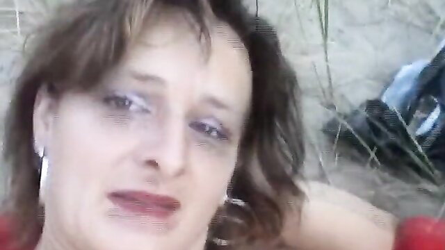 Older woman lying on sandy beach with subtle smile