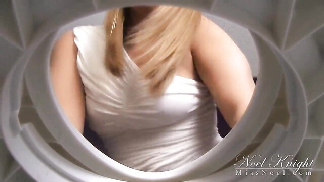 Miss Noel Knight blonde in white dress framed by toilet seat punishment tease