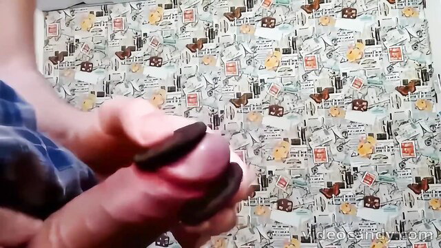 Man's hands holding cock between Oreo cookies on patterned bed