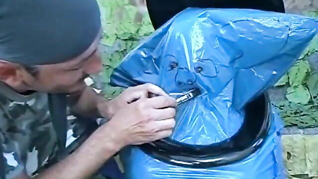 Man drawing crude face on blue trash bag in outdoor amateur tease