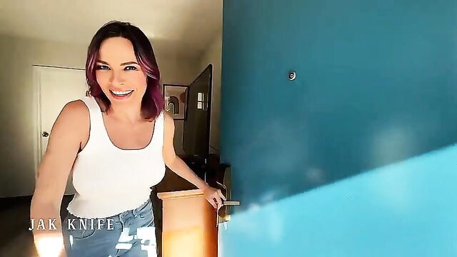 Hot MILF with purple hair smiling in tank top and jeans by door