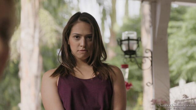 Latina beauty in tank top on porch, serious gaze