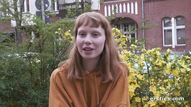 Adorable Norwegian redhead model in orange hoodie smiles outdoors