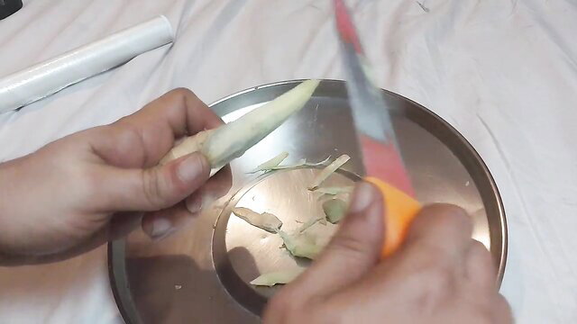 Woman cutting fresh ginger for first-time figging anal play in lesbian BDSM