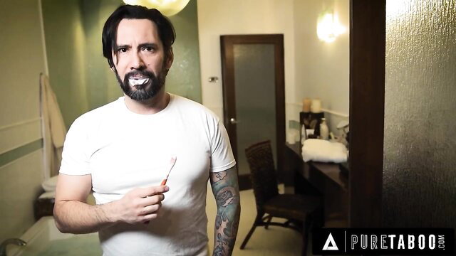 Tattooed muscular man with beard brushing teeth in white tee, homeless catfish vid
