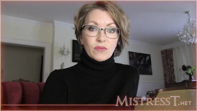 Mistress Tatjana in glasses and turtleneck assesses perversions