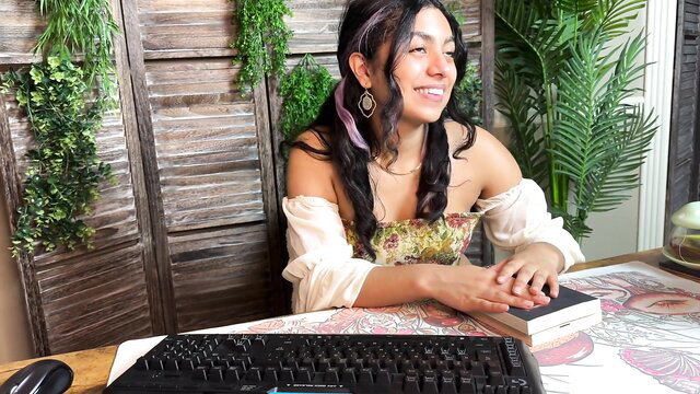 Smiling brunette Latina beauty in off-shoulder top at desk with book