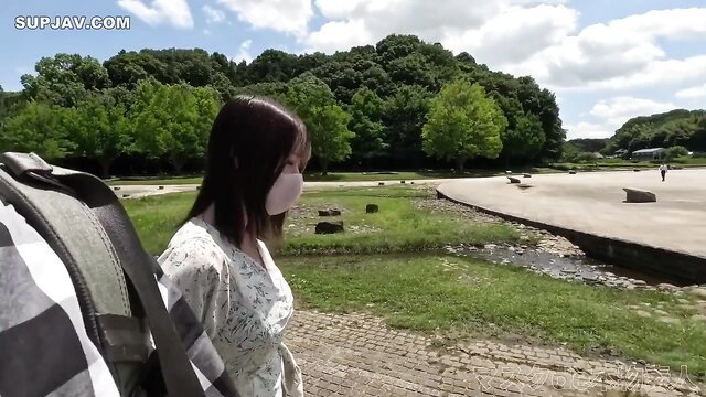 Japanese girl in plaid blouse and mask walks by lake in forest outdoors