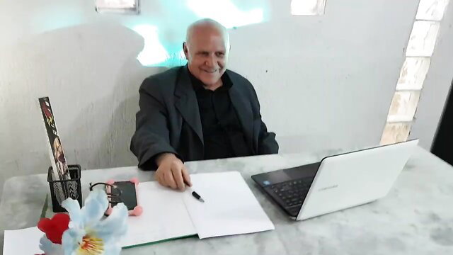 Bald granny Paty Booty smiling at desk in suit, Devil's Advocate adult video thumbnail