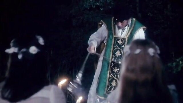 Vintage priest in green vestments censors ritual with brunette girls in woods