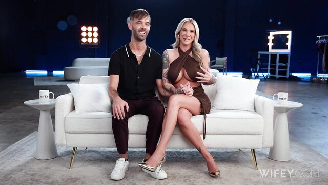 Kaci Kennedy tattooed hotwife in skimpy dress with Dakota on sofa