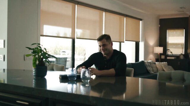 Man sitting at kitchen counter in modern home with plants and blinds