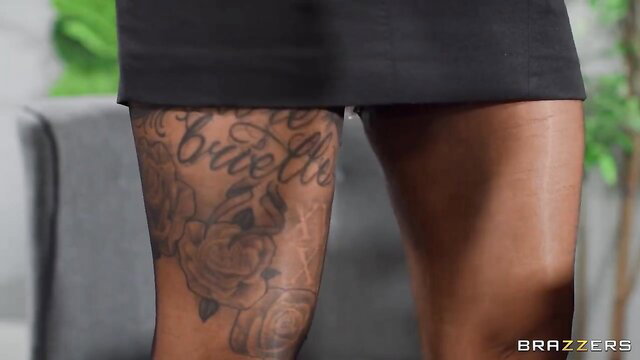 Busty Kerry Louise shows Brazzers tattoo on thick thighs in tight skirt