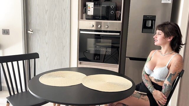Tattooed latina badvanne in lingerie at kitchen table, teasing cleavage
