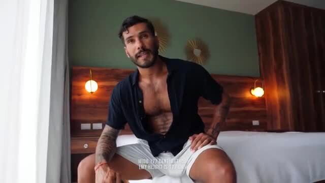 Jeus shirtless in unbuttoned shirt and shorts on bed, gay-for-pay handjob tease