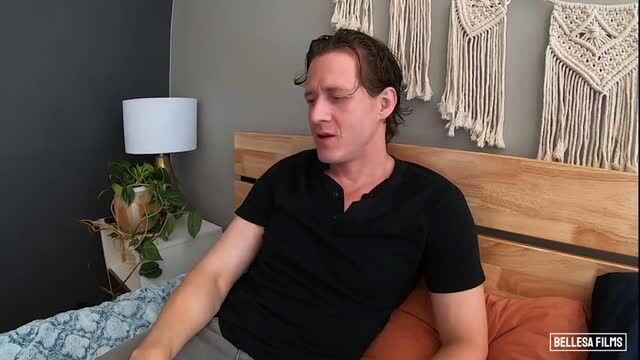 Handsome man with wavy hair sits on bed in black shirt, Bellesa MILF Obsession thumbnail