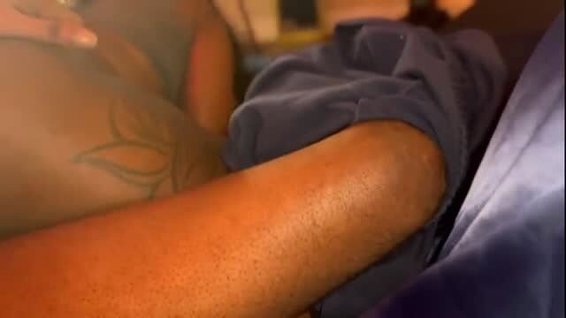 Tattooed ebony woman lying prone with back tattoo visible